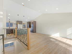 Corridor with light hardwood / wood-style floors and vaulted ceiling