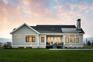 Back house at dusk featuring a lawn