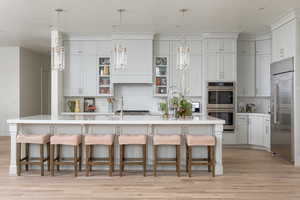 Kitchen featuring hanging light fixtures, a kitchen bar, stainless steel appliances, and a kitchen island with sink