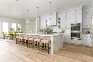 Kitchen with a kitchen breakfast bar, pendant lighting, an island with sink, and stainless steel double oven