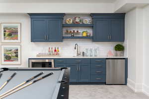 Bar with blue cabinetry, backsplash, and light colored carpet