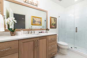 Bathroom featuring toilet, vanity, tile patterned floors, and an enclosed shower