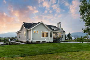 Back house at dusk with a sunroom, a mountain view, and a lawn