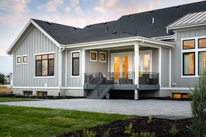 Back house at dusk with a lawn and a patio