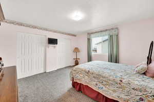 Bedroom featuring carpet flooring, a textured ceiling, and two closets