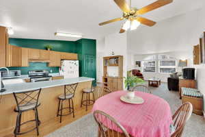 Carpeted dining room featuring ceiling fan and lofted ceiling