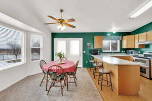 Dining area featuring ceiling fan, sink, and lofted ceiling