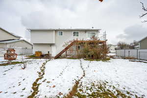 Snow covered back of property featuring a deck