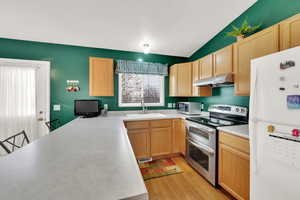 Kitchen featuring white fridge, double oven range, sink, and light brown cabinetry