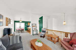 Living room with carpet flooring, ceiling fan, and vaulted ceiling