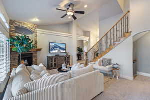 Carpeted living room featuring ceiling fan, a fireplace, and vaulted ceiling