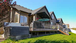 Rear view of property with a deck and a yard