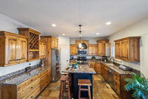 Kitchen featuring appliances with stainless steel finishes, a kitchen island, dark stone countertops, and sink