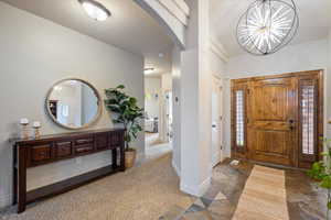 Carpeted foyer entrance featuring a chandelier