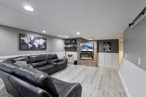 Living room with a barn door, light hardwood / wood-style floors, and a brick fireplace