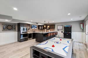 Game room with light wood-type flooring and wine cooler