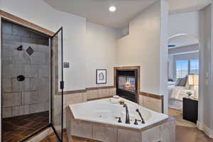 Bathroom featuring tile patterned flooring, separate shower and tub, and a tiled fireplace