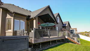 Back of house featuring a lawn and a wooden deck