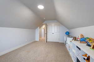 Additional living space with light colored carpet and lofted ceiling