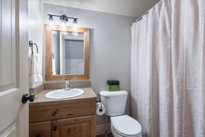 Bathroom with a textured ceiling, vanity, toilet, and curtained shower