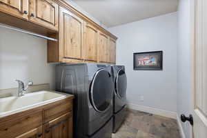 Laundry area featuring washer and clothes dryer, cabinets, and sink