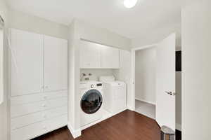 Laundry area with separate washer and dryer, dark wood-type flooring, and cabinets