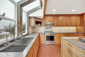 Kitchen featuring a skylight, stainless steel range with gas cooktop, sink, and tasteful backsplash