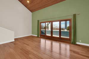 Empty room with light hardwood / wood-style floors, wood ceiling, high vaulted ceiling, and french doors