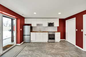 Kitchen featuring backsplash, sink, white cabinetry, and stainless steel appliances