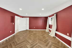 Empty room with electric panel and parquet flooring