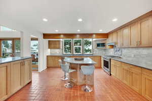 Kitchen featuring sink, a center island, backsplash, a breakfast bar area, and appliances with stainless steel finishes