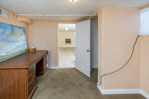 Hallway with carpet flooring and a textured ceiling