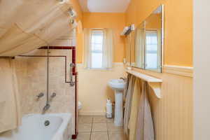 Full bathroom featuring tiled shower / bath combo, sink, tile patterned flooring, toilet, and lofted ceiling