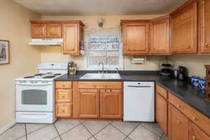 Kitchen with light tile patterned floors, white appliances, a textured ceiling, and sink