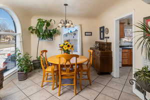 Tiled dining room featuring sink and an inviting chandelier