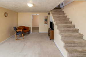 Interior space featuring a textured ceiling and light carpet