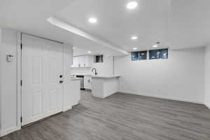 Kitchen featuring kitchen peninsula, light hardwood / wood-style floors, white cabinetry, and sink