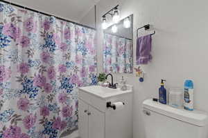 Bathroom featuring a shower with curtain, vanity, and toilet