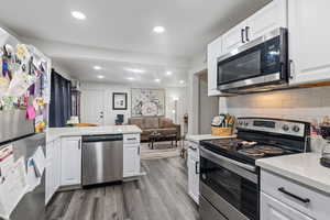 Kitchen featuring white cabinets, backsplash, and stainless steel appliances