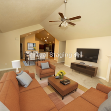 Carpeted living room with ceiling fan and vaulted ceiling