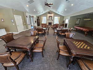 Carpeted dining space featuring a textured ceiling, ceiling fan, lofted ceiling, and pool table