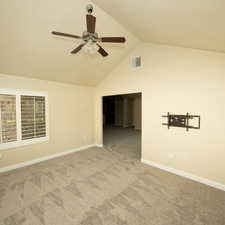 Carpeted spare room featuring ceiling fan and high vaulted ceiling