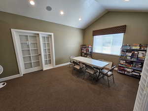 Dining space with lofted ceiling and dark colored carpet