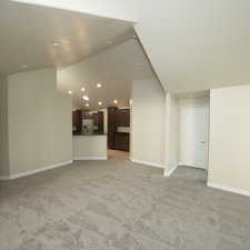 Unfurnished living room featuring light carpet and lofted ceiling