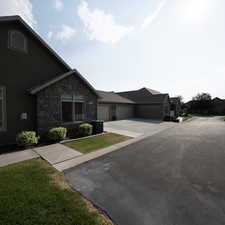 View of front facade with a garage, central air condition unit, and a front lawn