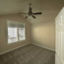 Carpeted spare room with ceiling fan and lofted ceiling