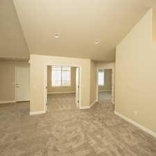 Empty room with light carpet and lofted ceiling