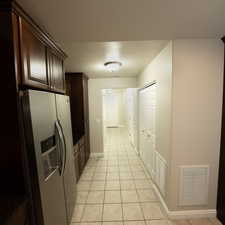 Kitchen featuring dark brown cabinets, stainless steel fridge with ice dispenser, a textured ceiling, and light tile patterned floors