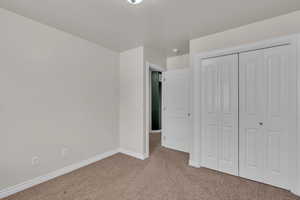 Unfurnished bedroom with light carpet and a closet