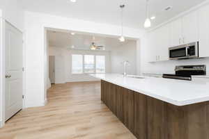 Kitchen featuring ceiling fan, sink, stainless steel appliances, pendant lighting, and dark brown cabinets